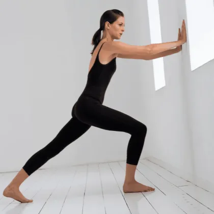 A woman doing a calf stretch against a white wall